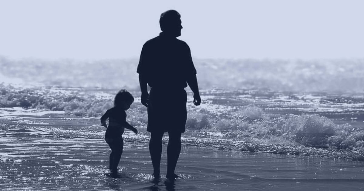 Father with child at the beach walking though waves
